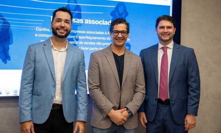 Três participantes do painel da AvenpesBR sobre reforma tributária e Fundos de Compensação, reunidos diante do telão do evento no Café Hall Fecomércio, em Vitória, Espírito Santo.